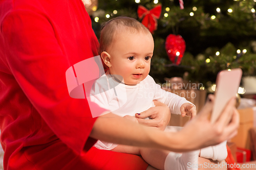 Image of mother with baby girl and smartphone on christmas