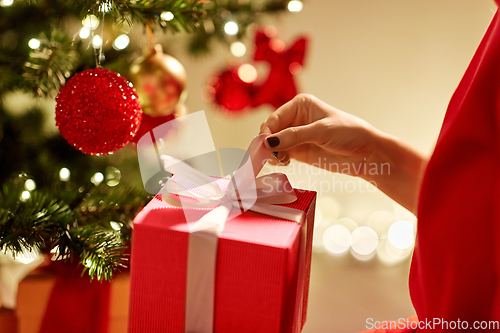 Image of close up of woman with gift box at christmas tree