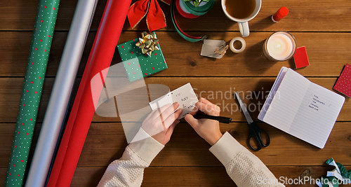 Image of hands attaching name tag to christmas gift