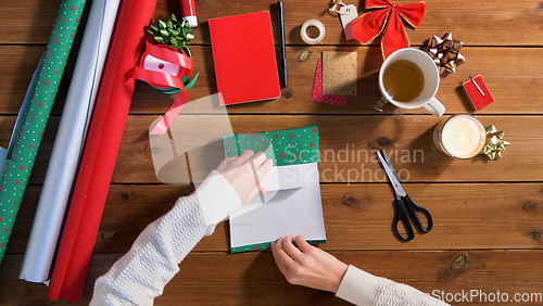 Image of hands wrapping christmas gift into paper at home