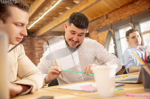 Image of Young caucasian colleagues working together in a office using modern devices and gadgets