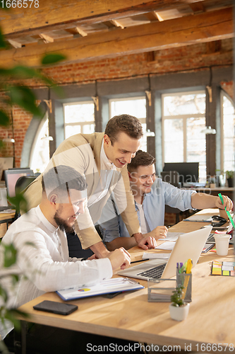 Image of Young caucasian colleagues working together in a office using modern devices and gadgets