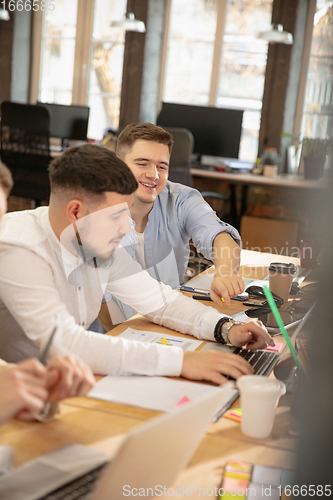 Image of Young caucasian colleagues working together in a office using modern devices and gadgets