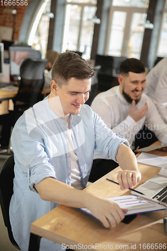 Image of Young caucasian colleagues working together in a office using modern devices and gadgets