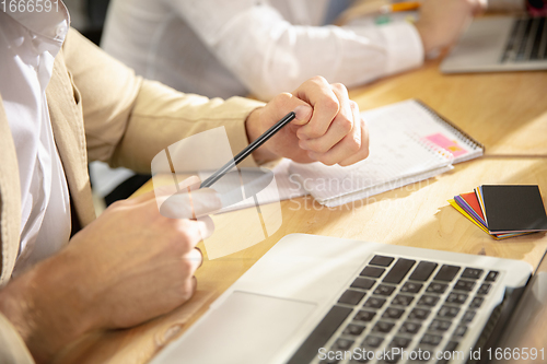 Image of Hands of colleagues working together in a office using modern devices and gadgets during creative meeting. Close up.