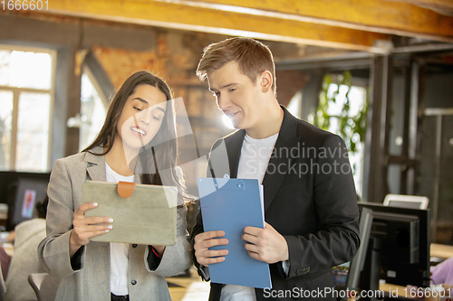 Image of Young caucasian colleagues working together in a office using modern devices and gadgets