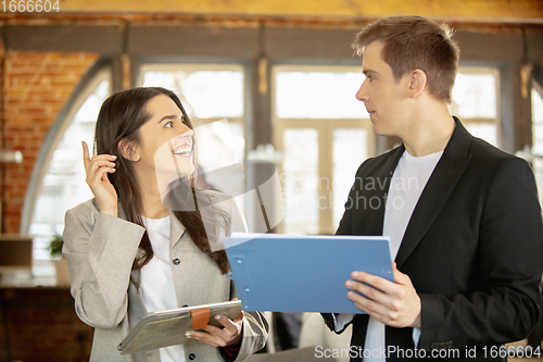 Image of Young caucasian colleagues working together in a office using modern devices and gadgets