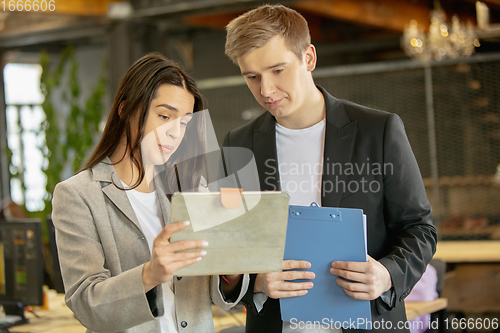 Image of Young caucasian colleagues working together in a office using modern devices and gadgets