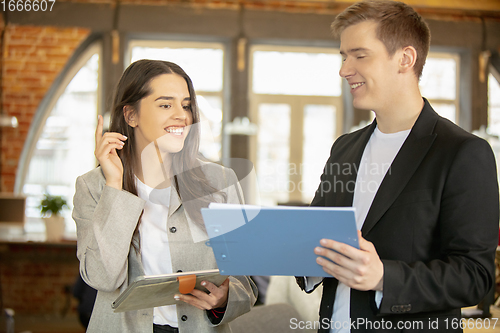 Image of Young caucasian colleagues working together in a office using modern devices and gadgets