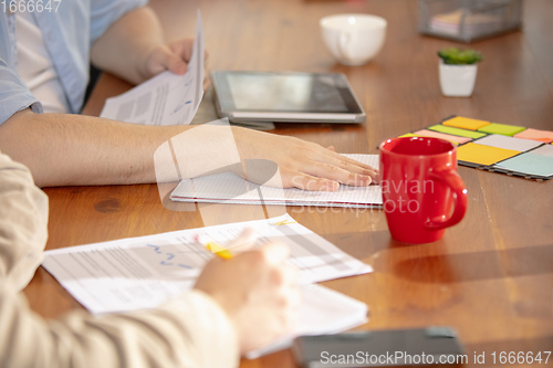 Image of Hands of colleagues working together in a office using modern devices and gadgets during creative meeting. Close up.