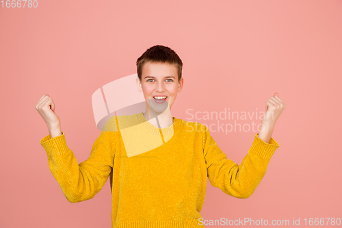 Image of Caucasian girl\'s portrait isolated on coral pink studio background with copyspace