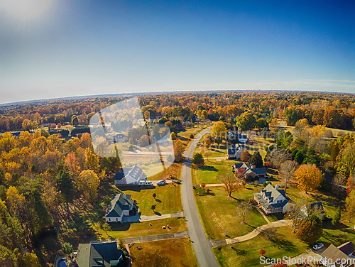 Image of aerial view of colorful trees in a neighborhood before sunset