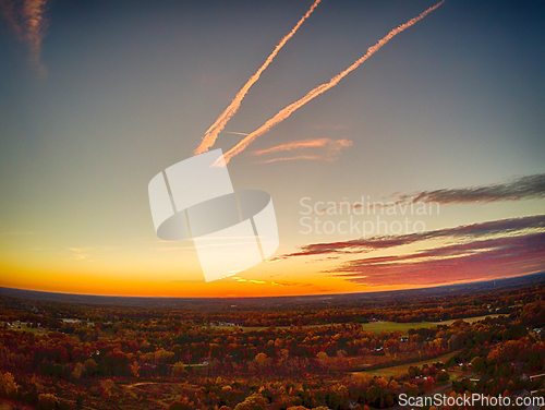 Image of aerial view of colorful trees in a neighborhood before sunset