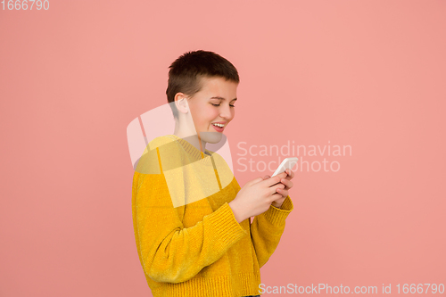 Image of Caucasian girl\'s portrait isolated on coral pink studio background with copyspace