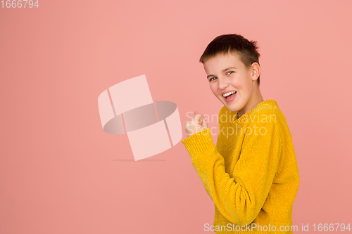 Image of Caucasian girl\'s portrait isolated on coral pink studio background with copyspace