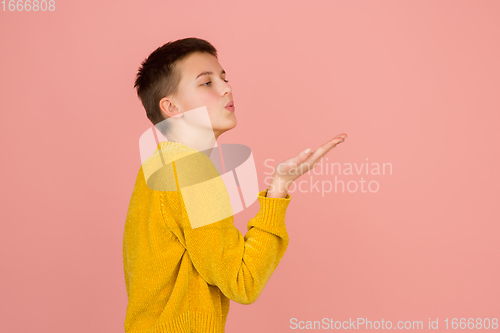 Image of Caucasian girl\'s portrait isolated on coral pink studio background with copyspace