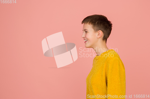 Image of Caucasian girl\'s portrait isolated on coral pink studio background with copyspace