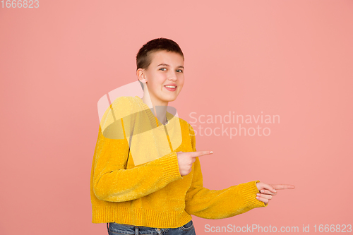 Image of Caucasian girl\'s portrait isolated on coral pink studio background with copyspace