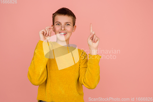 Image of Caucasian girl\'s portrait isolated on coral pink studio background with copyspace