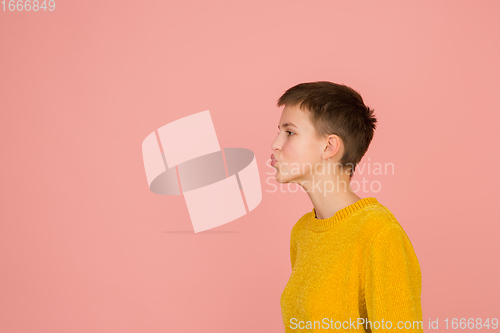 Image of Caucasian girl\'s portrait isolated on coral pink studio background with copyspace