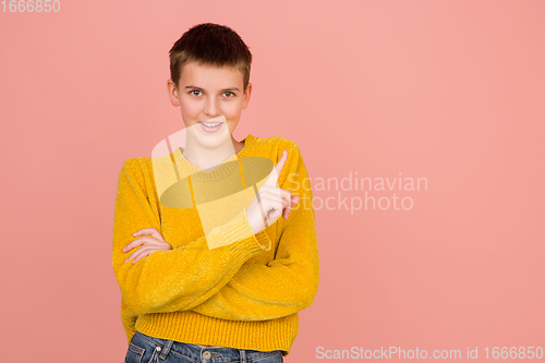 Image of Caucasian girl\'s portrait isolated on coral pink studio background with copyspace