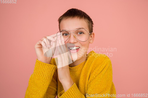 Image of Caucasian girl\'s portrait isolated on coral pink studio background with copyspace