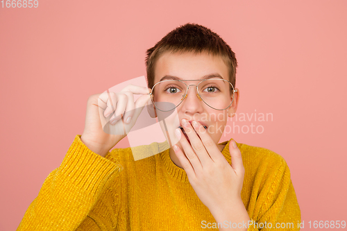 Image of Caucasian girl\'s portrait isolated on coral pink studio background with copyspace