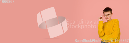 Image of Caucasian girl\'s portrait isolated on coral pink studio background with copyspace