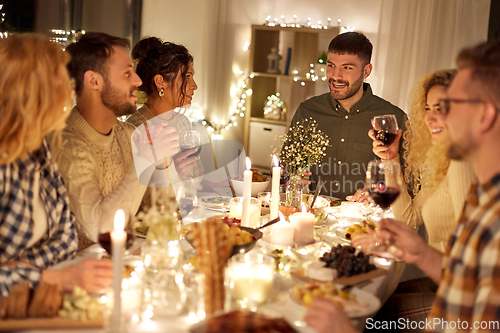 Image of happy friends drinking red wine at christmas party