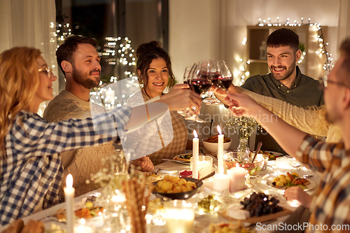 Image of happy friends drinking red wine at christmas party