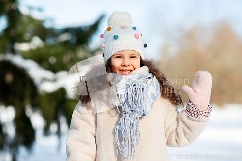 Image of happy little girl waving hand outdoors in winter