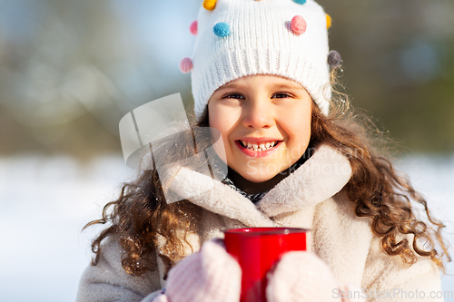 Image of little girl with cup of hot tea in winter park