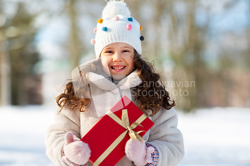 Image of happy girl with red christmas gift in winter park