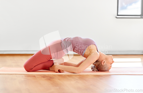 Image of young woman doing fish pose at yoga studio