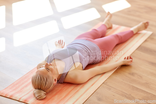 Image of woman doing yoga corpse pose at studio