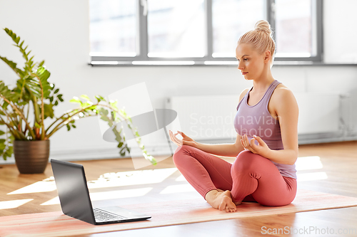 Image of woman with laptop in lotus pose at yoga studio