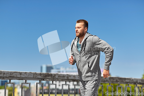 Image of happy young man running across city bridge