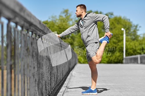 Image of man stretching leg on bridge