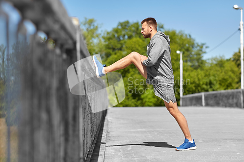 Image of man stretching leg on bridge