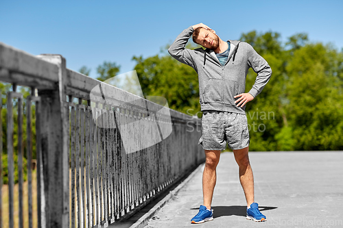 Image of man stretching neck on bridge