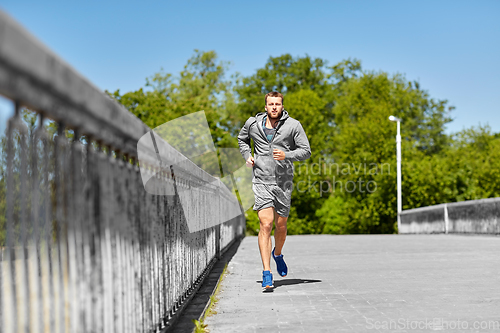 Image of happy young man running across city bridge