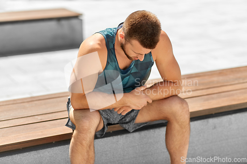 Image of young man sitting on bench outdoors