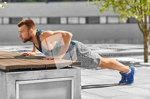 Image of young man doing push ups on city street