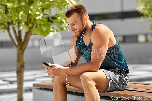 Image of young athlete man with earphones and smartphone