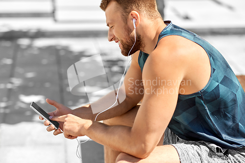 Image of young athlete man with earphones and smartphone