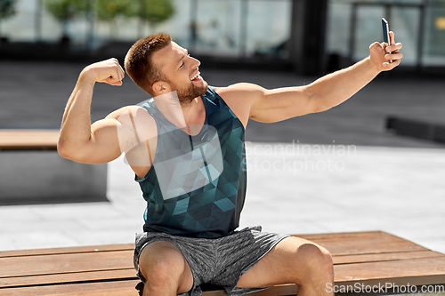 Image of man taking selfie with phone and showing bicep