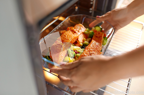 Image of woman cooking food in oven at home kitchen