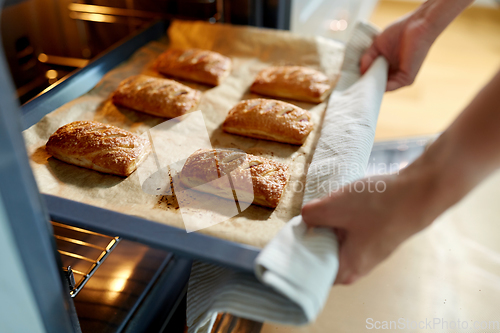 Image of woman cooking food in oven at home kitchen