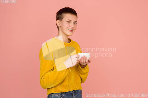 Image of Caucasian girl\'s portrait isolated on coral pink studio background with copyspace