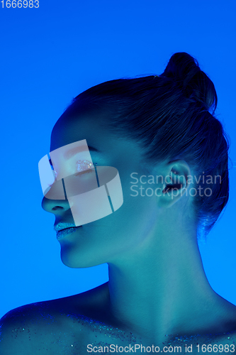 Image of Handsome woman\'s portrait isolated on blue studio background in neon light, monochrome